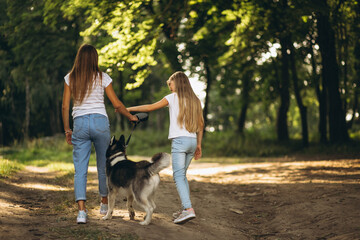 Naklejka na ściany i meble Two sisters with their dog in park