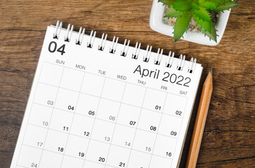 Fototapeta premium April 2022 desk calendar with plant on wooden table.