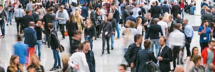 crowd of trade show people rushing in a hall, banner size. ideal for websites and magazines layouts