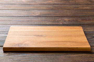 Perspective view of wooden cutting board on wooden background. Empty space for your design