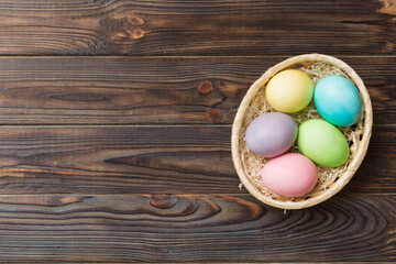 Multi colors Easter eggs in the woven basket on colored background . Pastel color Easter eggs. holiday concept with copy space