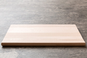Perspective view of wooden cutting board on cement background. Empty space for your design