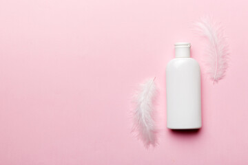 Set of skin care serums on pink pastel background with ostrich feathers. Spa cosmetic product, cream jar, branding mock up, top view with copy space