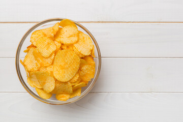 Potato chips on bowl isolated on colored background. Delicious crispy potato chips in bowl. Space for text. Top view