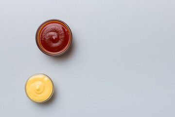 Bowl of ketchup and cheese sauce on colored background, top view with copy space