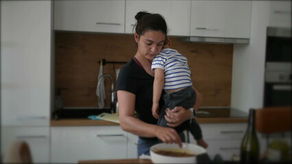 Mother cooking while holding baby toddler child