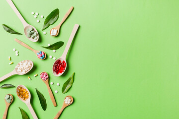 Top view Variety of vitamin and mineral pills in wooden spoon on Colored background. Top view of assorted pharmaceutical medicine pills. Dietary supplement healthcare product