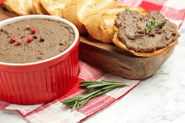 Tasty liver pate, rosemary and slices of bread on white marble table, closeup