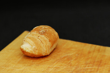 One delicious croissant on a wooden board