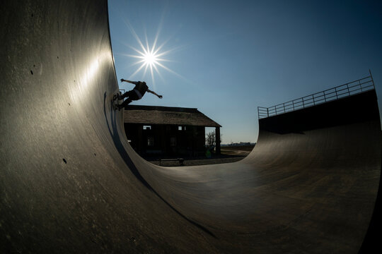 Young skateboarder in action, on a vert ramp doing trick with big shadow