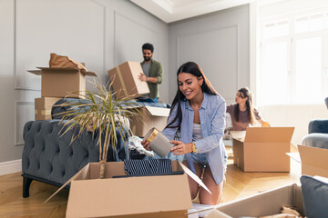 Woman unpacking her things from cardboard box after moving in in her new apartment.
