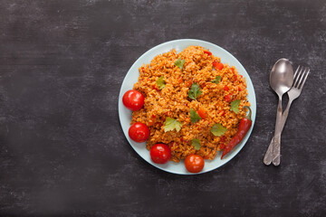 Jollof rice with parsley on a plate on a black background. National cuisine of Africa.