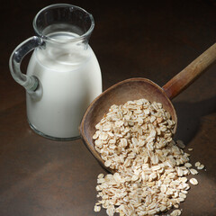 Oatmeal in a wooden bowl, oatmeal and cup of milk on the  table. Healthy eating