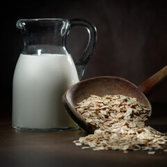 Oatmeal in a wooden bowl, oatmeal and cup of milk on the  table. Healthy eating