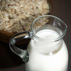 Oatmeal in a wooden bowl, oatmeal and cup of milk on the  table. Healthy eating