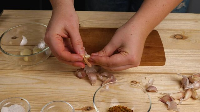 Peeling garlic from husks in the home kitchen. A woman's hands peel garlic and put it in a bowl. Healthy and wholesome food for every day