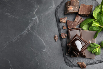 Tasty chocolate pieces with syrup and mint on black table, flat lay. Space for text
