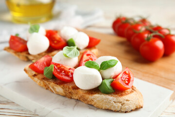 Fototapeta na wymiar Delicious sandwich with mozzarella, fresh tomatoes and basil on board