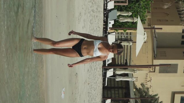 Beautiful caucasian girl with two ponytails in a bikini. A European woman with two bunches on the sides of her head is resting on the sea. Lely is sunbathing. The girl lies in the waves of the ocean.