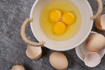 Whole eggs, broken eggs, yolk in a bowl on the table. Selective focus