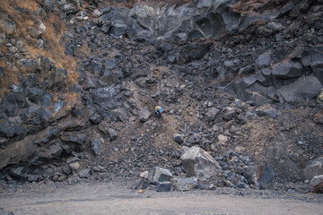 man breaking volcanic rock with metal hammer