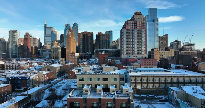 American city in fresh winter snow. City skyline on snowy day with blue sky. Aerial truck shot.