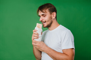A handsome young man holds a doner in his hand. delicious shawarma