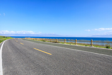 Empty asphalt highway and azure ocean nature scenery under blue sky