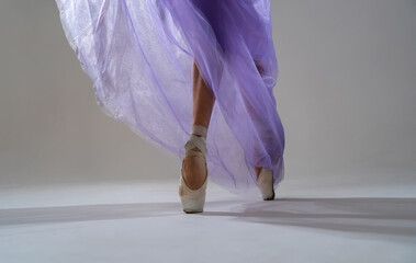 close-up view of dancing legs of ballerina in light blue soaring dress. Unrecognizable girl demonstrating ballet movements. Art, movement, inspiration concept