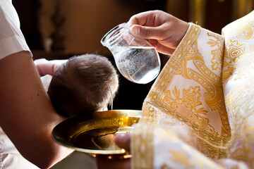Infant baptism.
Water is poured on the head of an infant. - obrazy, fototapety, plakaty