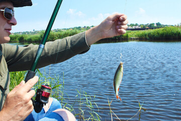 Caucasian young fisherman caught a fish with a bait. Catch fish on a maggot on a summer day on the river bank