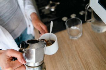 Fototapeta na wymiar Women pouring espresso coffee into a cup from a mocha pot. 