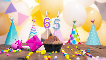 Happy birthday with a number of candles for sixty-five years on the background of balloons. A...