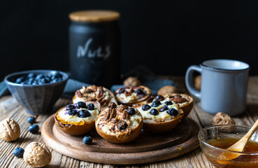 Backed pears with ricotta cheese, blueberries, pecan nuts and honey in rustic style concept