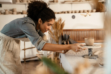 Young black ceramist woman sculpting in clay at her workshop