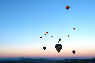 Colourful hot air balloons flying above the mountains, sunrise