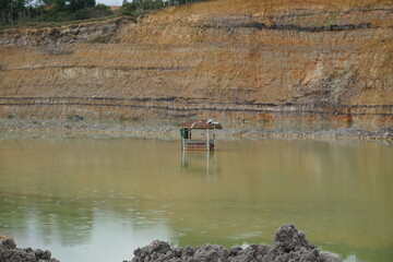 landscape photo of a small hut in a coal mine that is starting to sink in the lake and you can see the reflection too