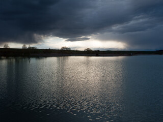 dramatic stormy dark sky over the pond at spring, almost monochrome,siluette