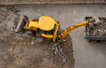 yellow excavator bucket loads into the truck old asphalt, top view