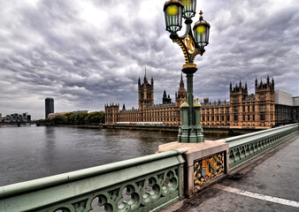 Fototapeta na wymiar Puente de Westminster y las casas del Parlamento bajo un cielo nublado y gris con sus faroles en primer plano.