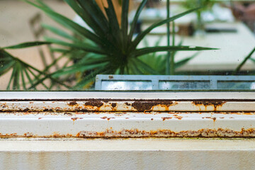 Close up of rust on old white iron window sill with a blurred background. Rust stains and corrosion cracking of window frame. Rusted bars on the windows in ruined abandoned building. Selective focus.