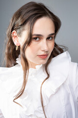 Young woman with long hair with dark brown eyes isolated on grey in white clothes