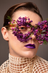 Young woman with eye mask made of small flowers with purple lips portrait