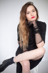 Fototapeta premium White young european woman sitting in total black isolated on grey