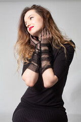 White young european woman in total black isolated on grey in gloves