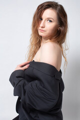 Fototapeta premium White young european woman with open shoulders in total black isolated on light grey