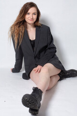 White young european woman with brown hair sitting isolated on light grey in total black