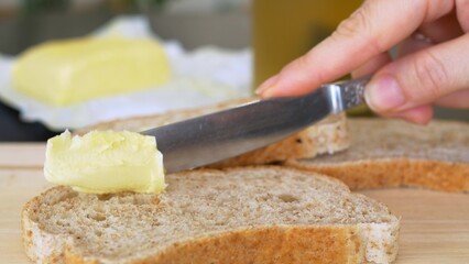 Close Up shot of a knife spreading butter on a piece of bread, tasty food being prepared for breakfast or lunch. Spreading Vegan Butter On Rye Bread Without Dairy And Eggs.