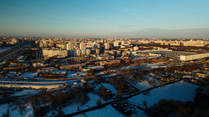 Suburb of a big city. City block from the height of the flight. City highway with busy traffic. Winter cityscape. Golden hour at sunset. Aerial photography.