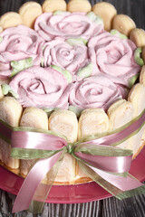 Cake with Savoiardi cookies and marshmallow roses. Tied with ribbon. The ribbon is tied into a bow.